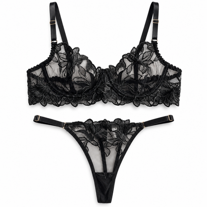 Black floral lace lingerie set featuring a sheer underwire bra and a matching thong with adjustable straps and gold-tone hardware, displayed on a clean white background.