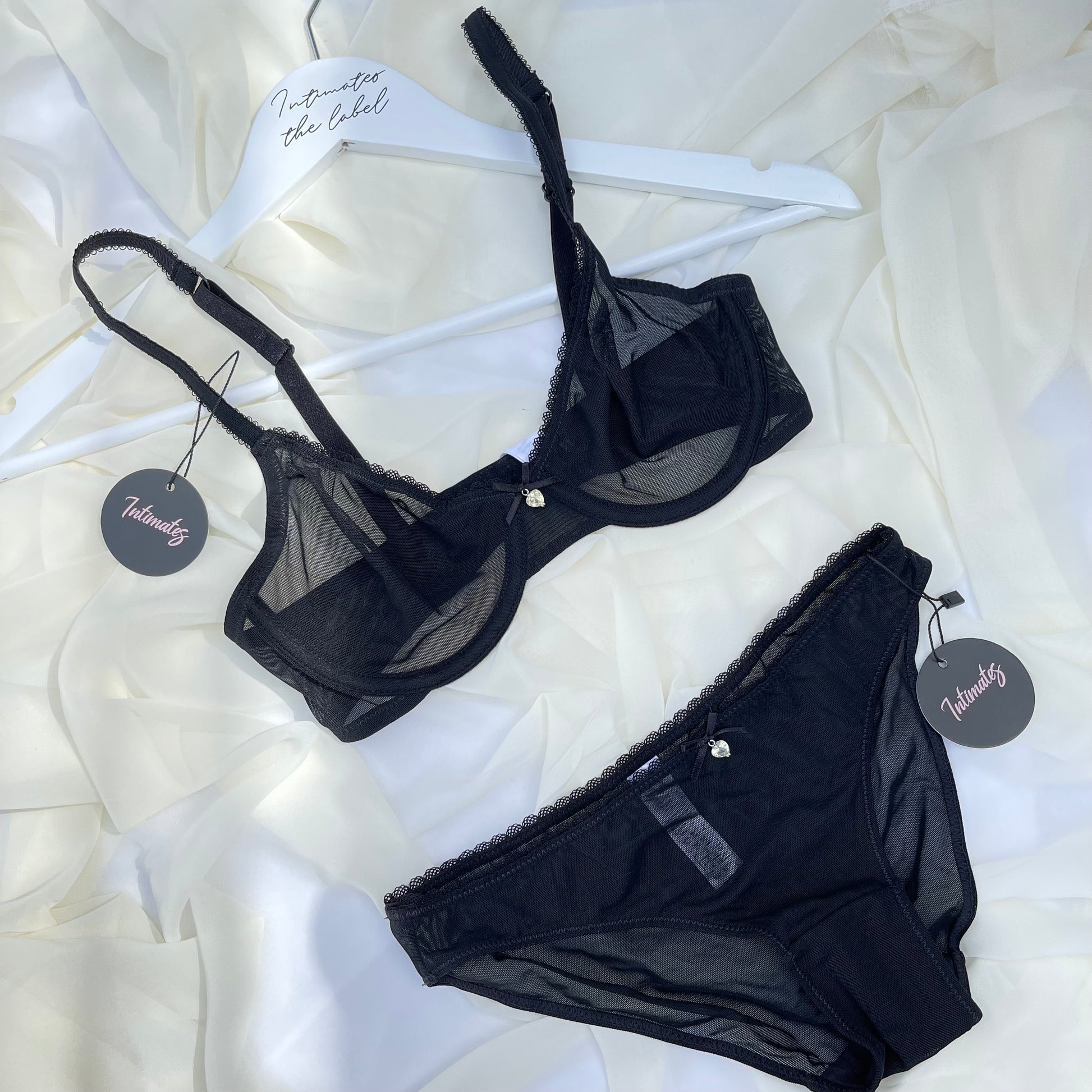 Black lingerie set with tags on a white textured background