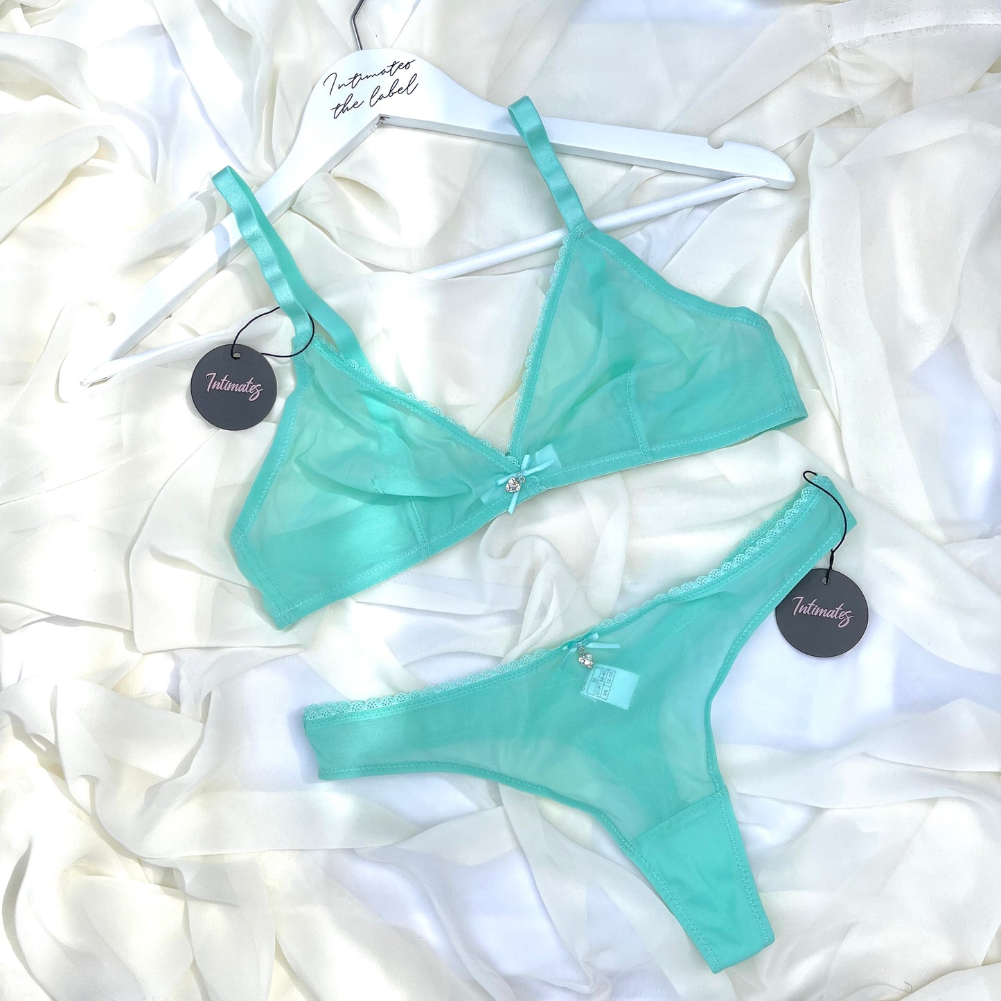 Mint green bra and panties set with tags on a white fabric background