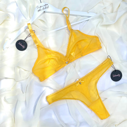 Yellow bra and panties set on a white fabric background 